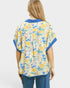 Woman wearing a floral patterned shirt with blue accents on a plain background