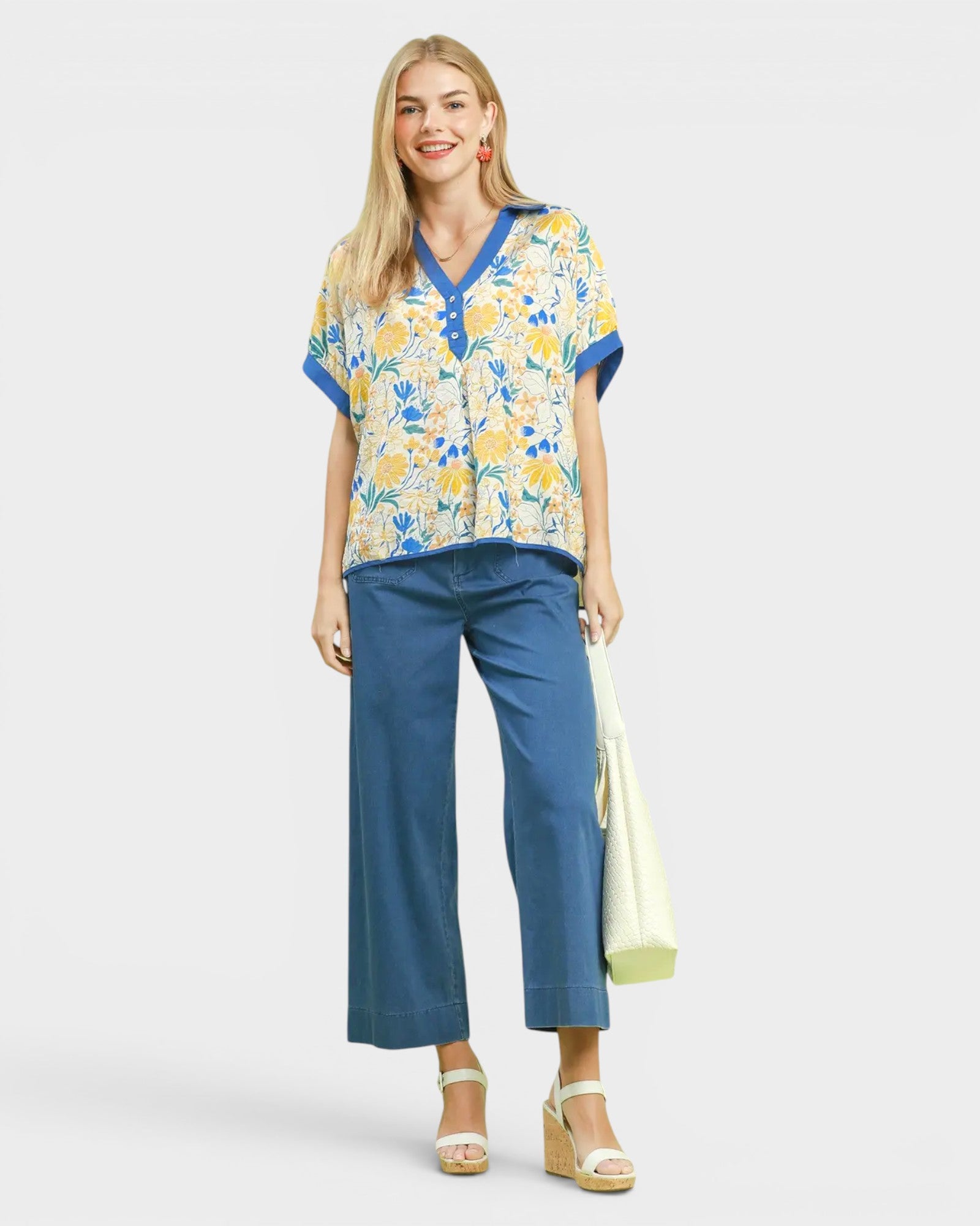 Woman wearing a floral blouse and blue pants on a white background