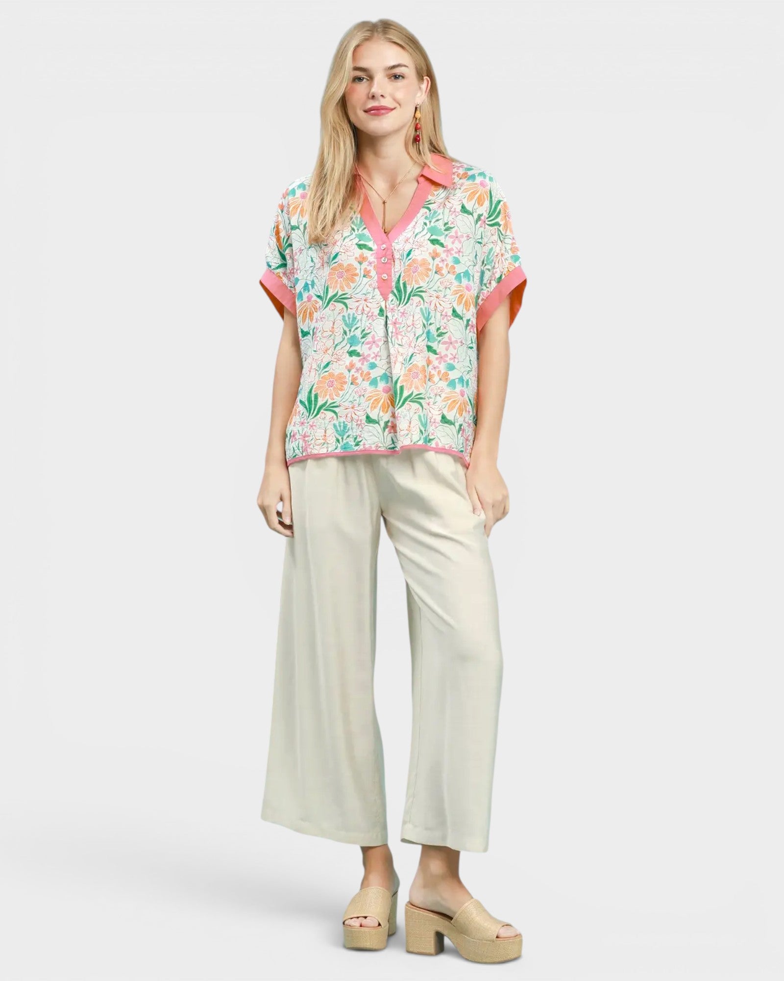 Woman wearing a floral blouse and beige pants on a white background