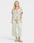 Woman wearing a floral blouse and beige pants on a white background