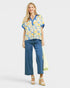 Woman wearing a floral blouse and blue pants on a white background