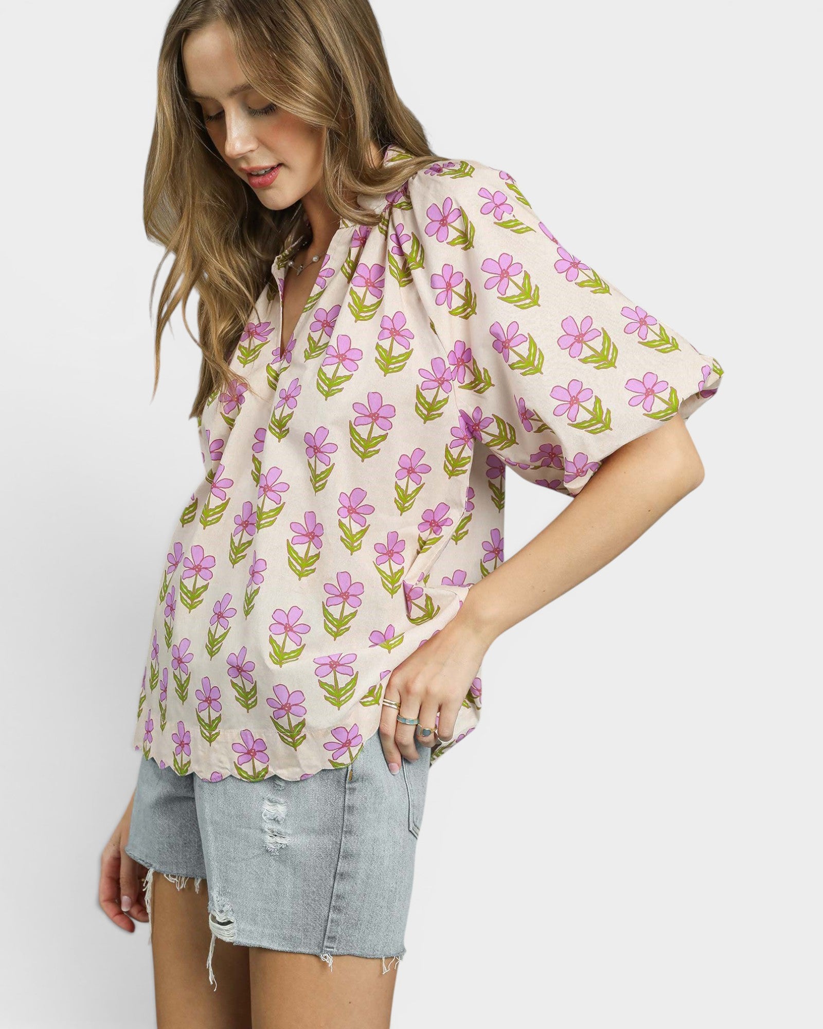 Woman wearing a floral blouse and denim shorts on a white background