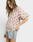 Woman wearing a floral blouse and denim shorts on a white background