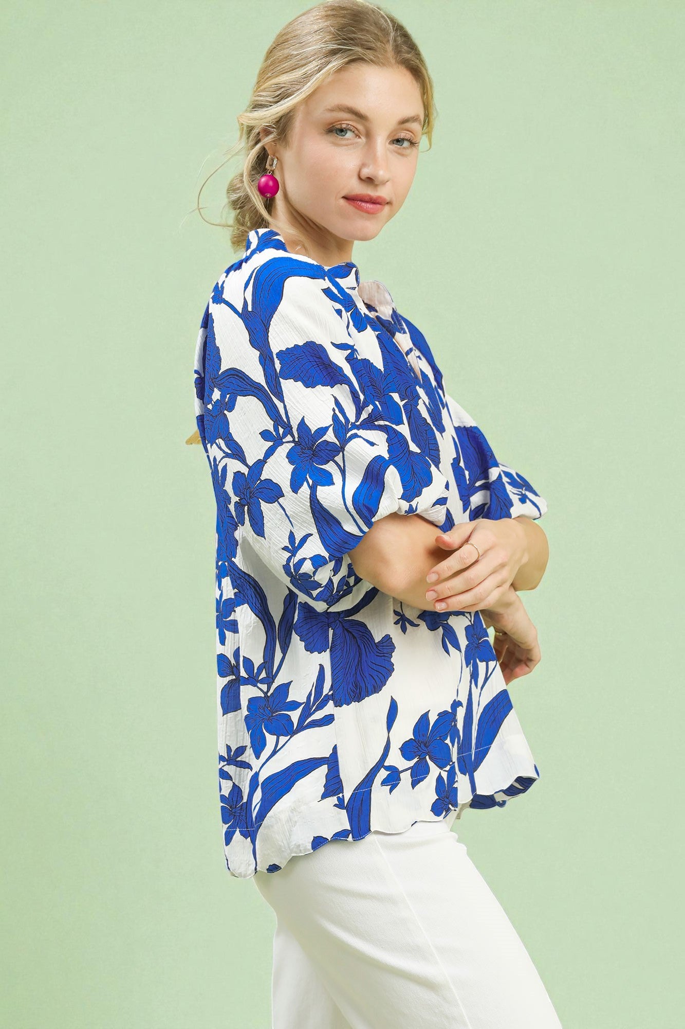 Woman wearing a blue and white floral blouse against a light green background