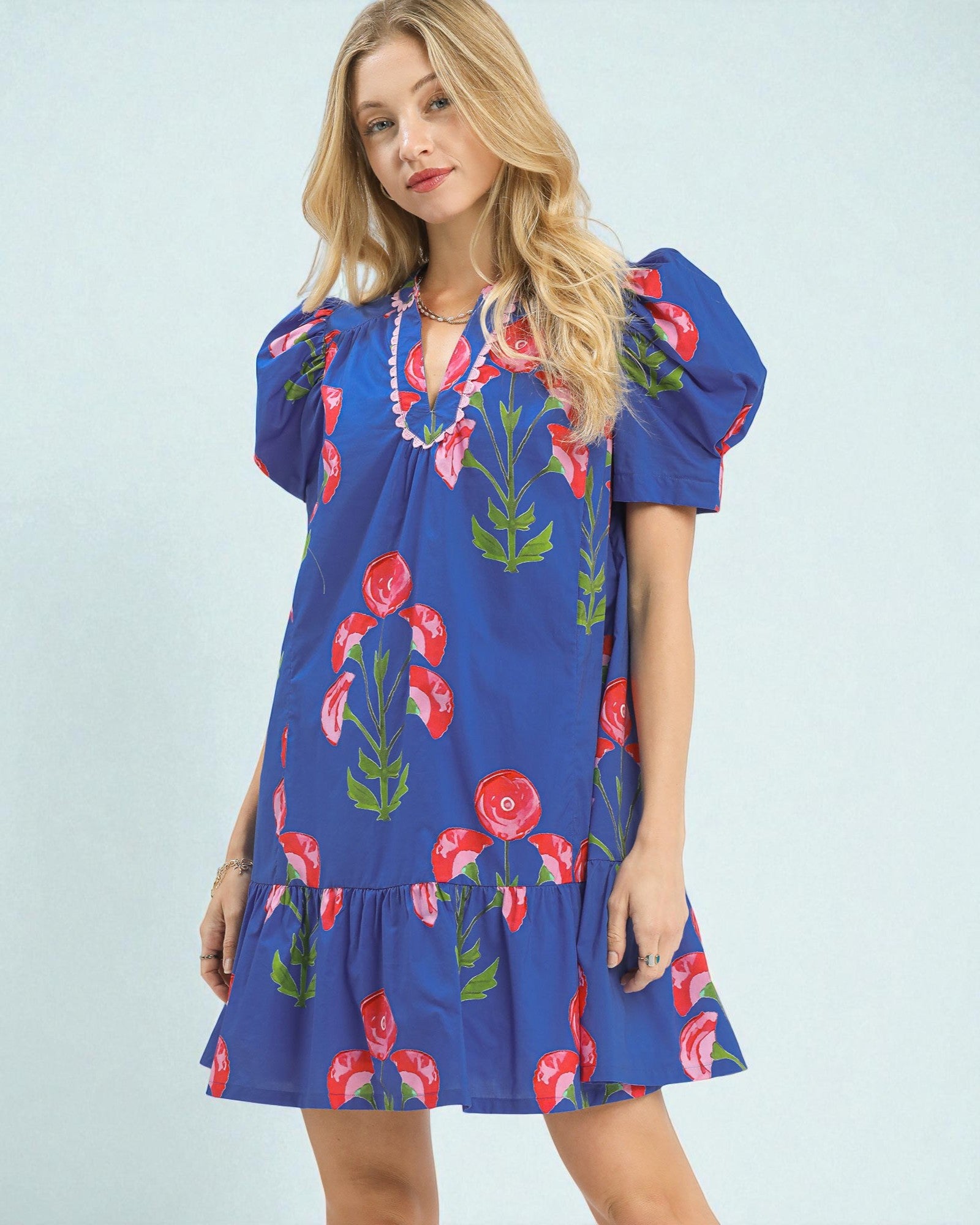 Woman wearing a blue dress with floral patterns on a light blue background