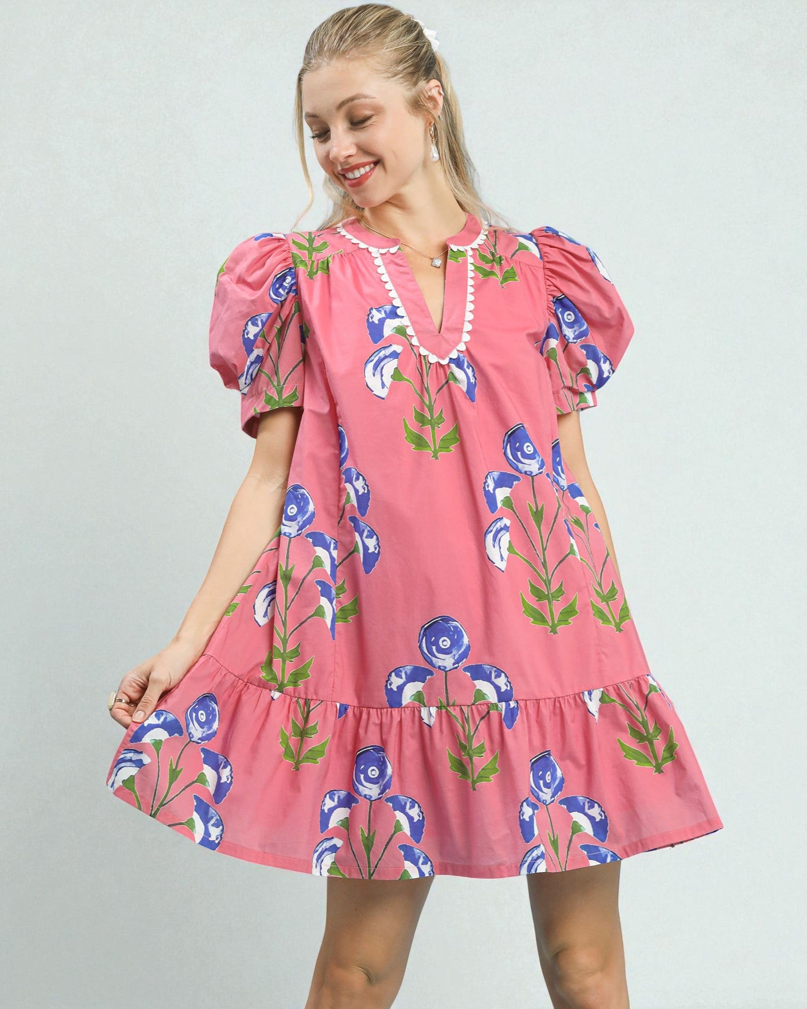 Woman wearing a pink floral dress against a plain background