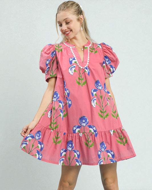 Woman wearing a pink floral dress against a plain background