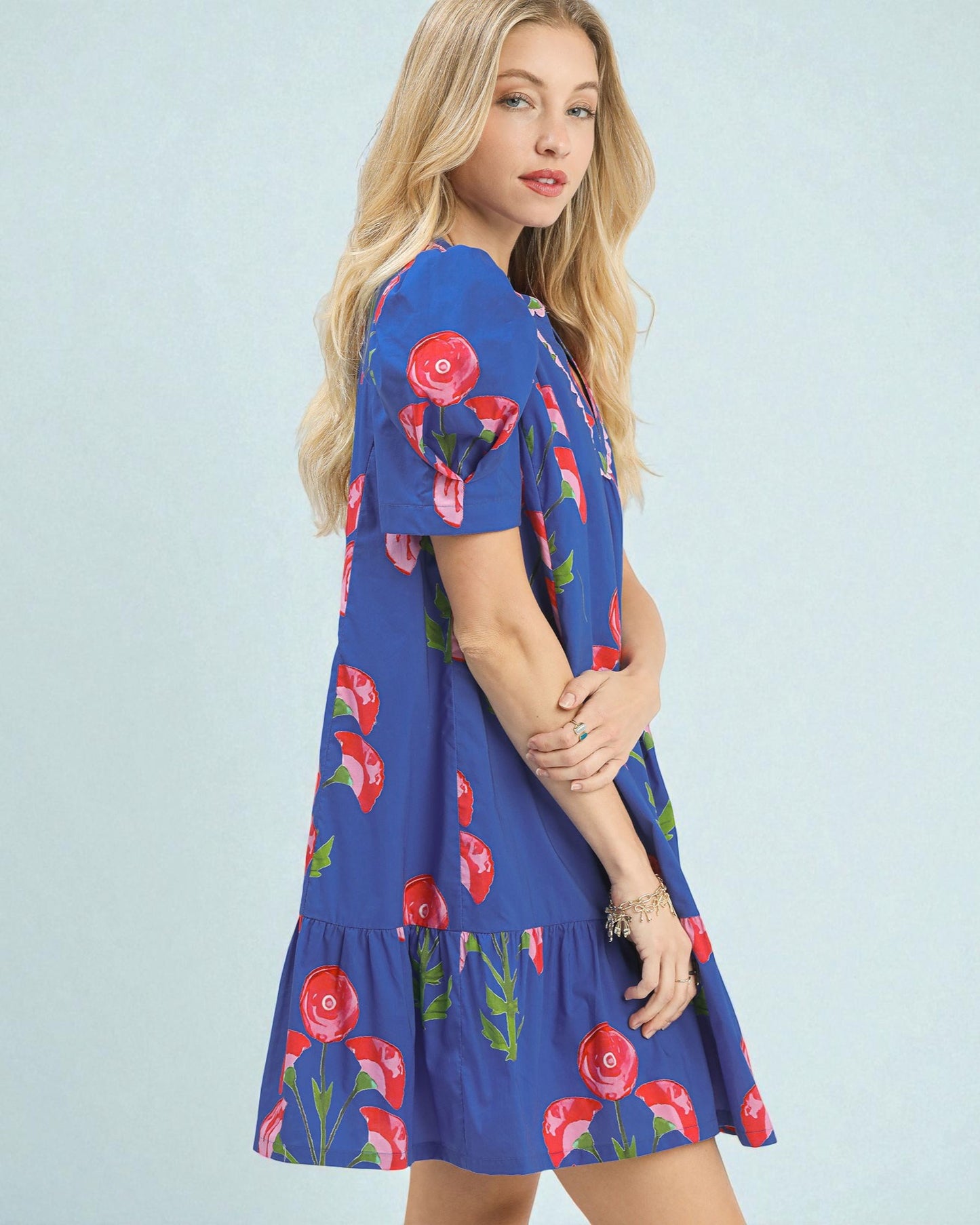 Woman wearing a blue dress with floral patterns on a light blue background