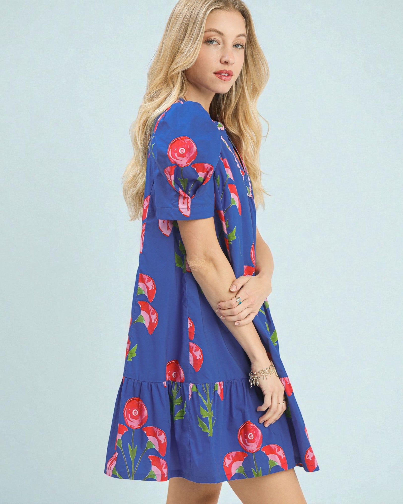 Woman wearing a blue dress with floral patterns on a light blue background