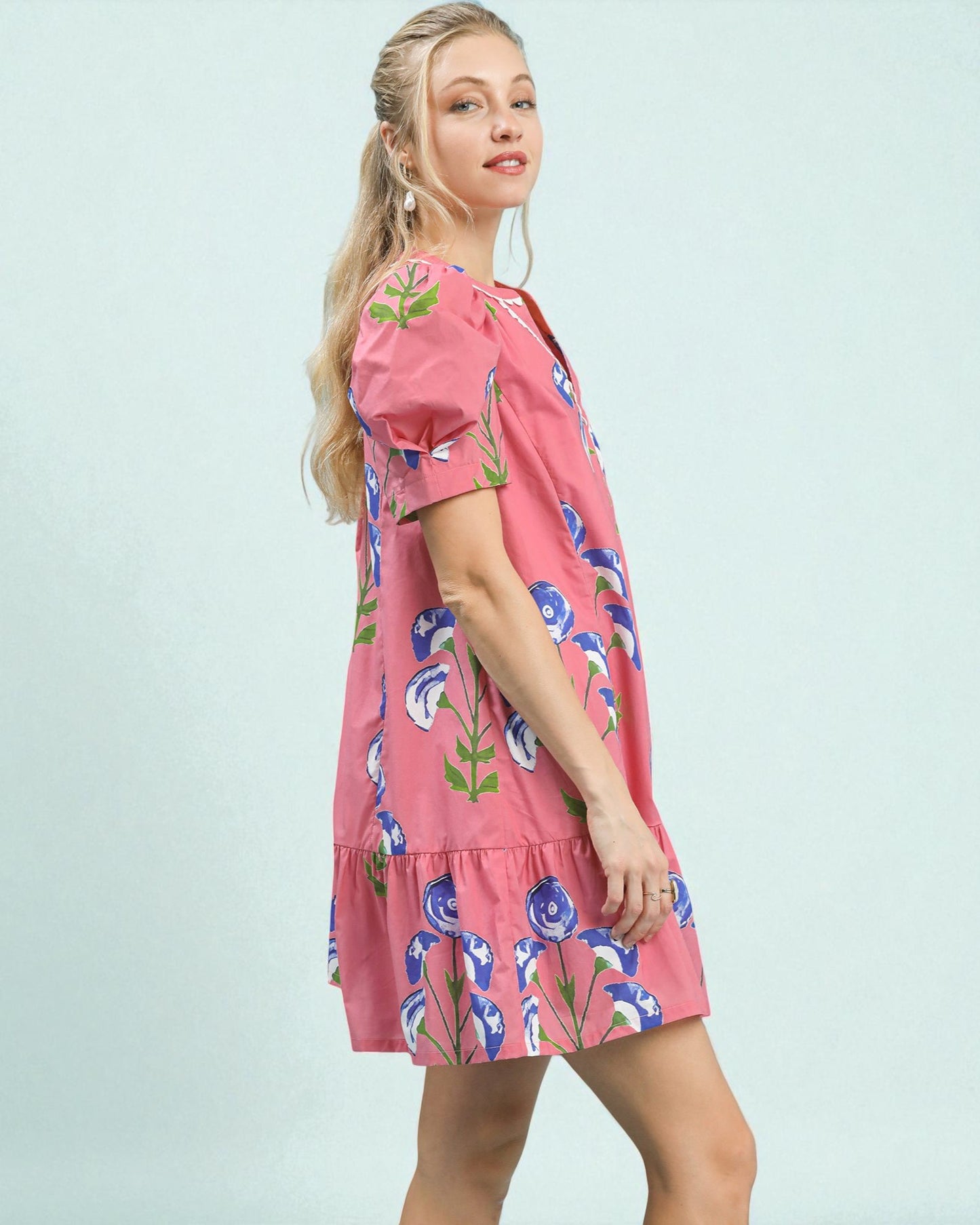 Woman wearing a pink floral dress against a light blue background