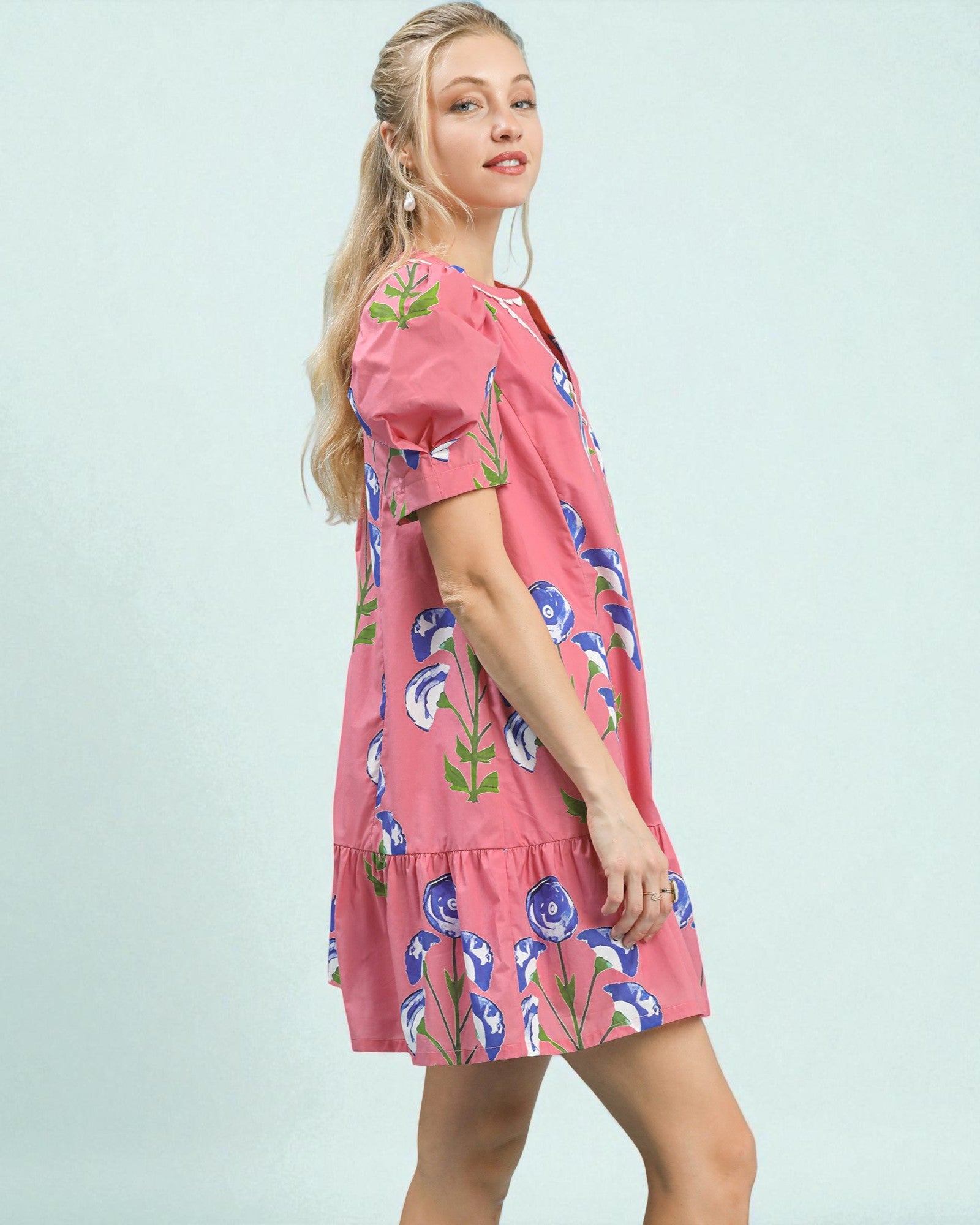 Woman wearing a pink floral dress against a light blue background