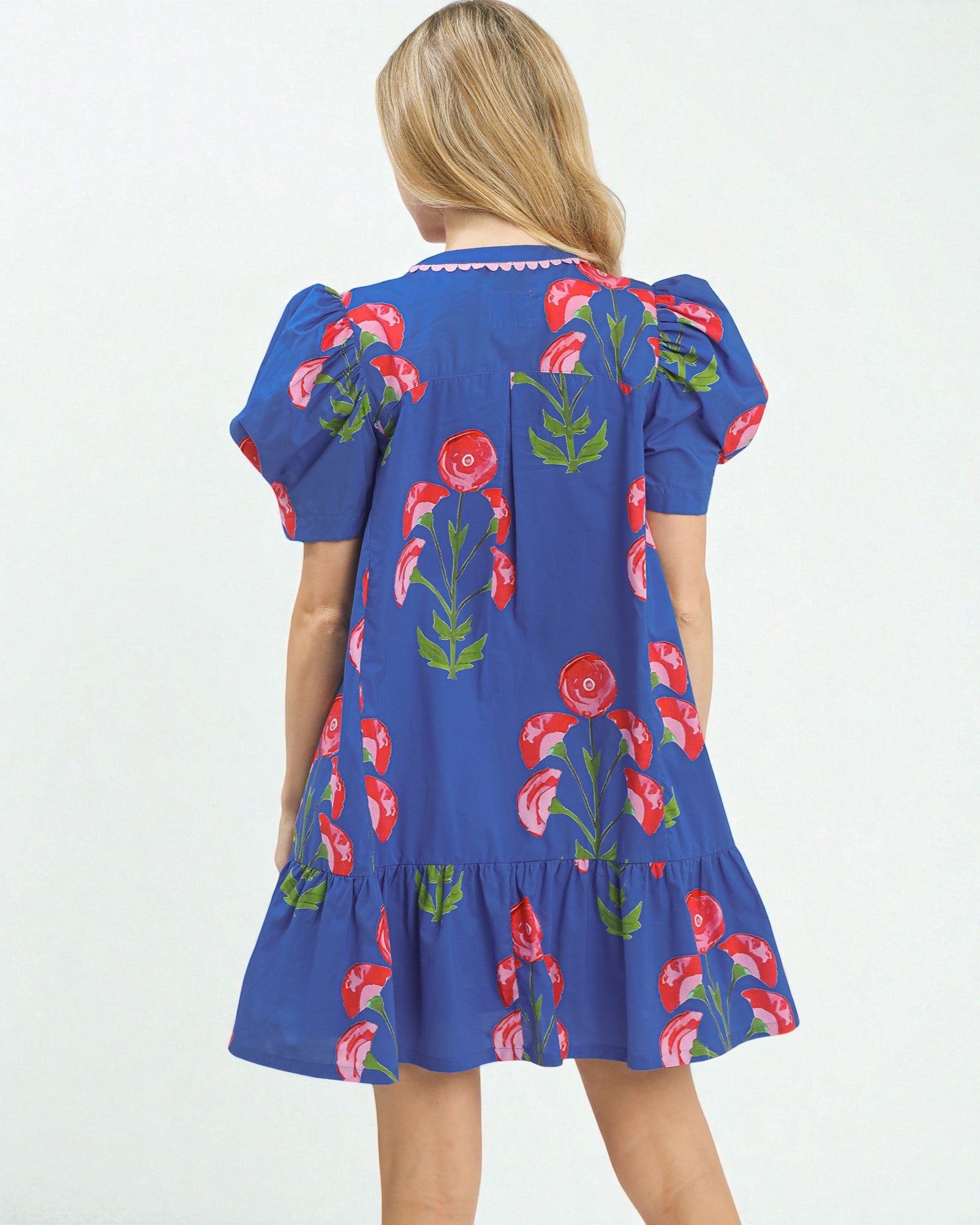 Woman wearing a blue dress with red floral patterns on a white background