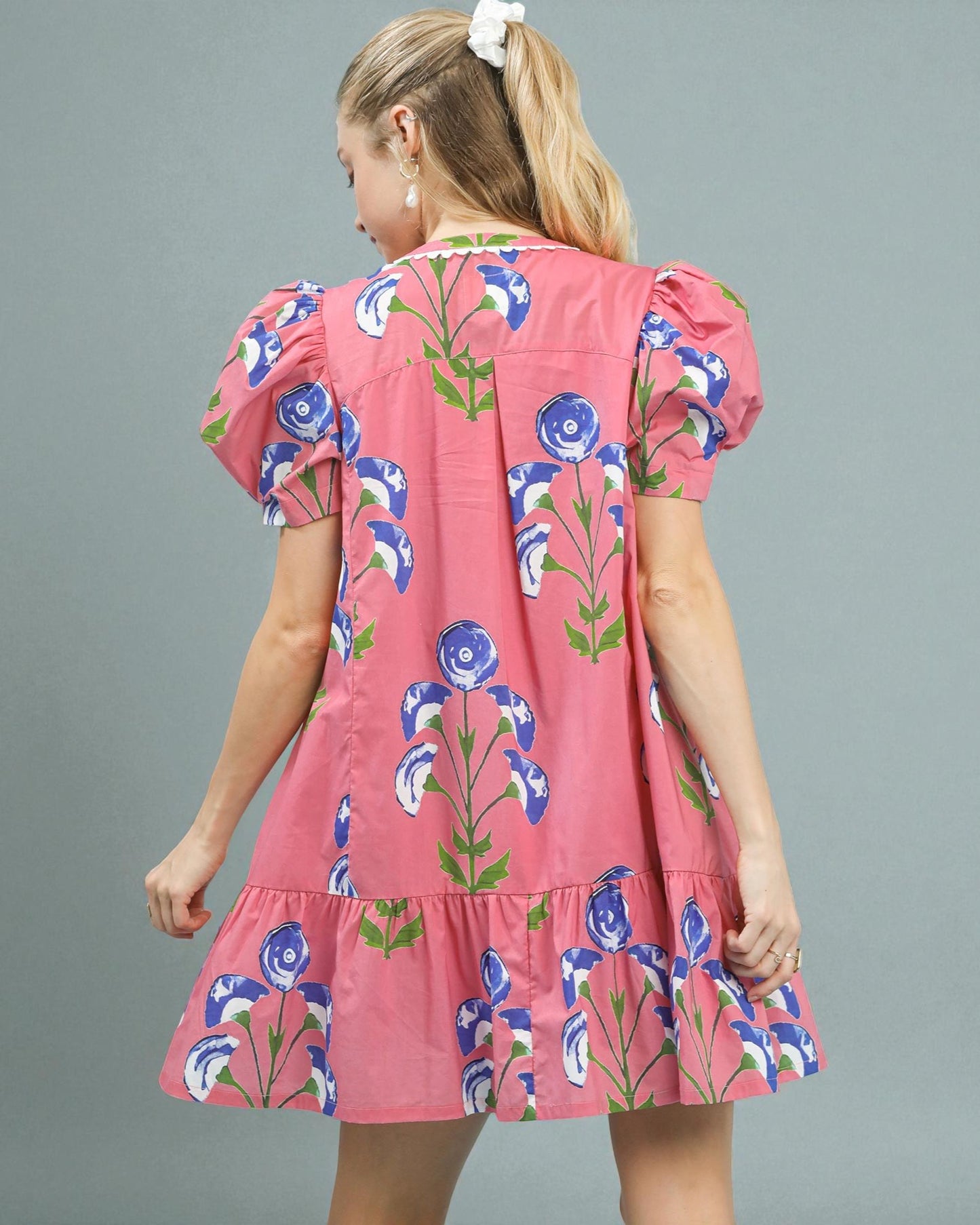 Pink dress with floral pattern worn by a person on a gray background