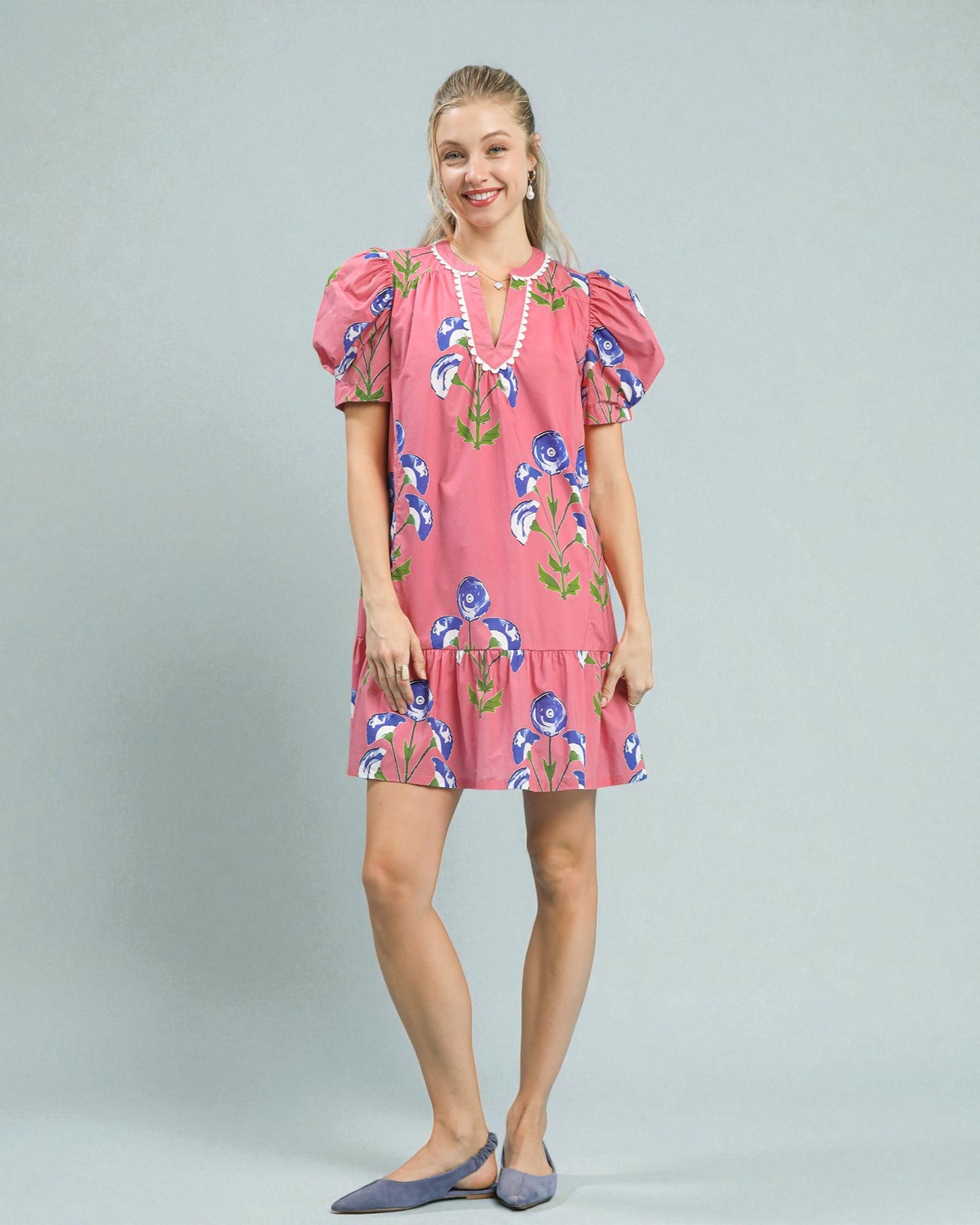 Woman wearing a pink floral dress on a gray background