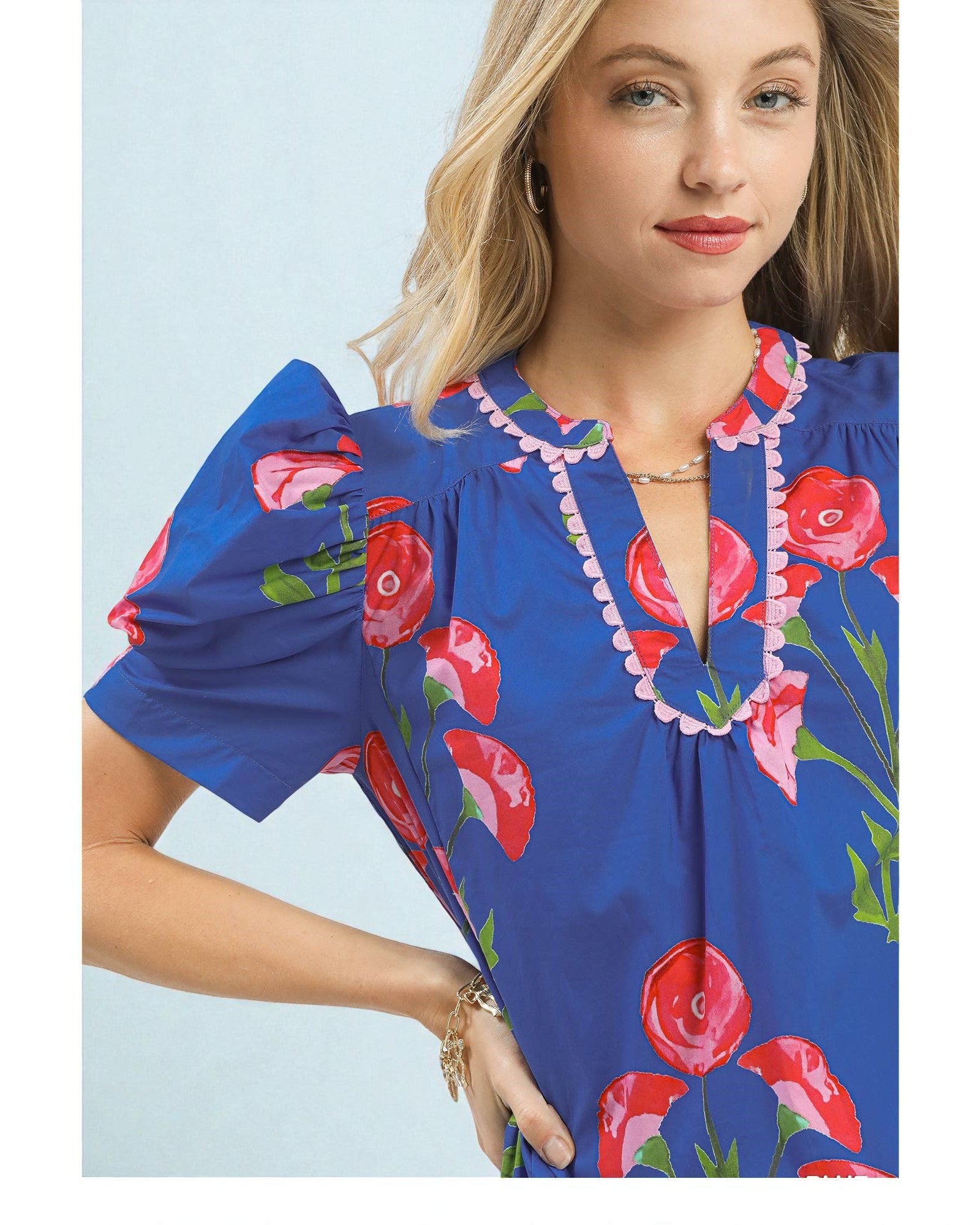 Woman wearing a blue dress with red floral patterns on a light blue background