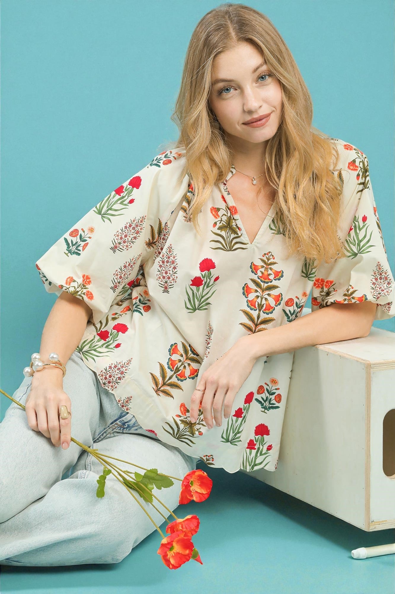 Woman wearing a floral dress sitting on a blue background