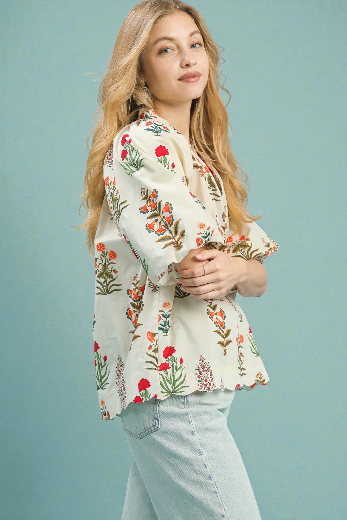 Woman wearing a floral embroidered blouse against a light blue background