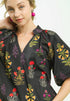 Woman wearing a black floral embroidered dress against a white background