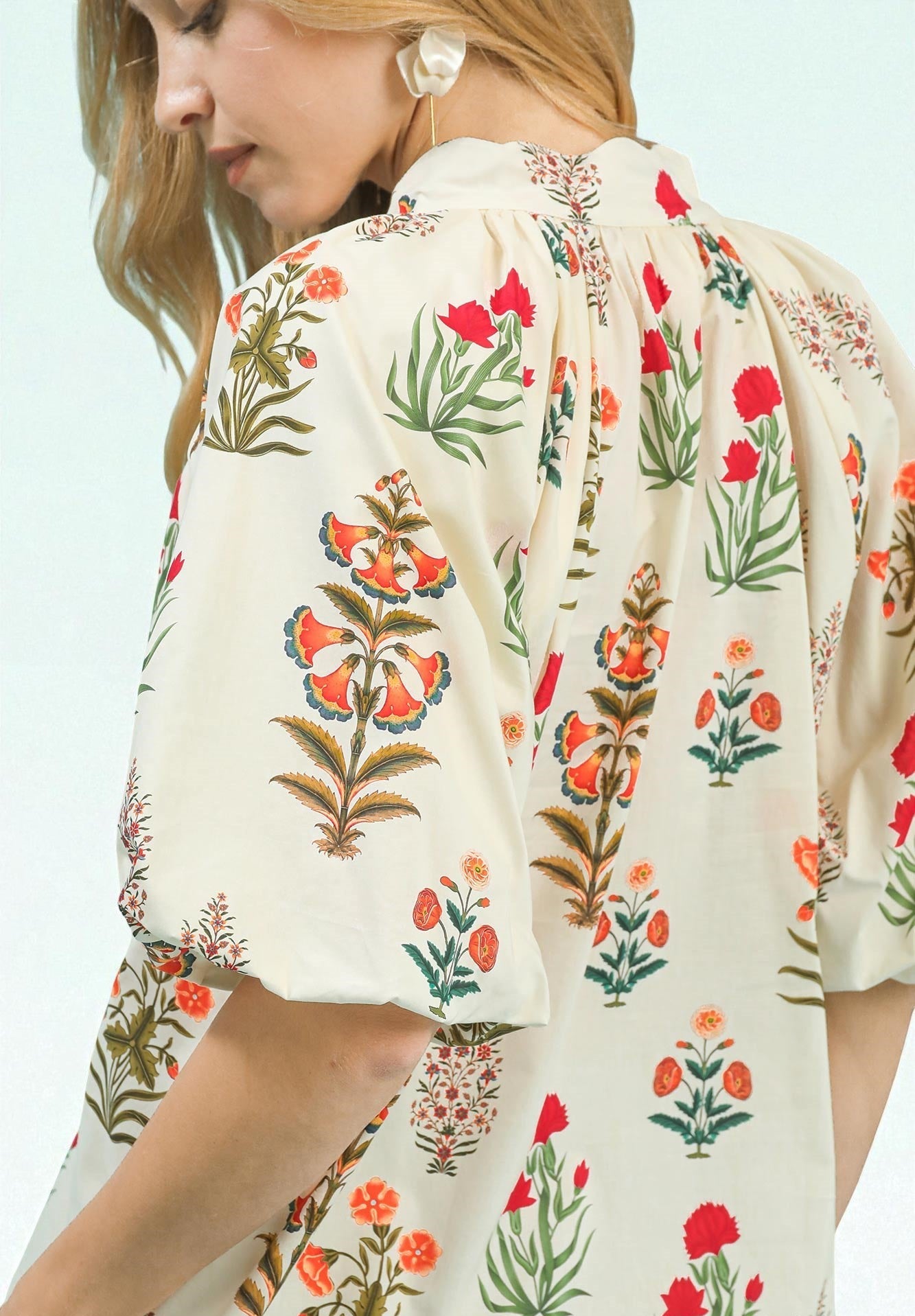 Woman wearing a floral patterned blouse with a light background