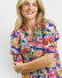 Woman wearing a colorful floral dress against a plain background