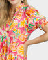 Woman wearing a colorful floral dress with a pink background