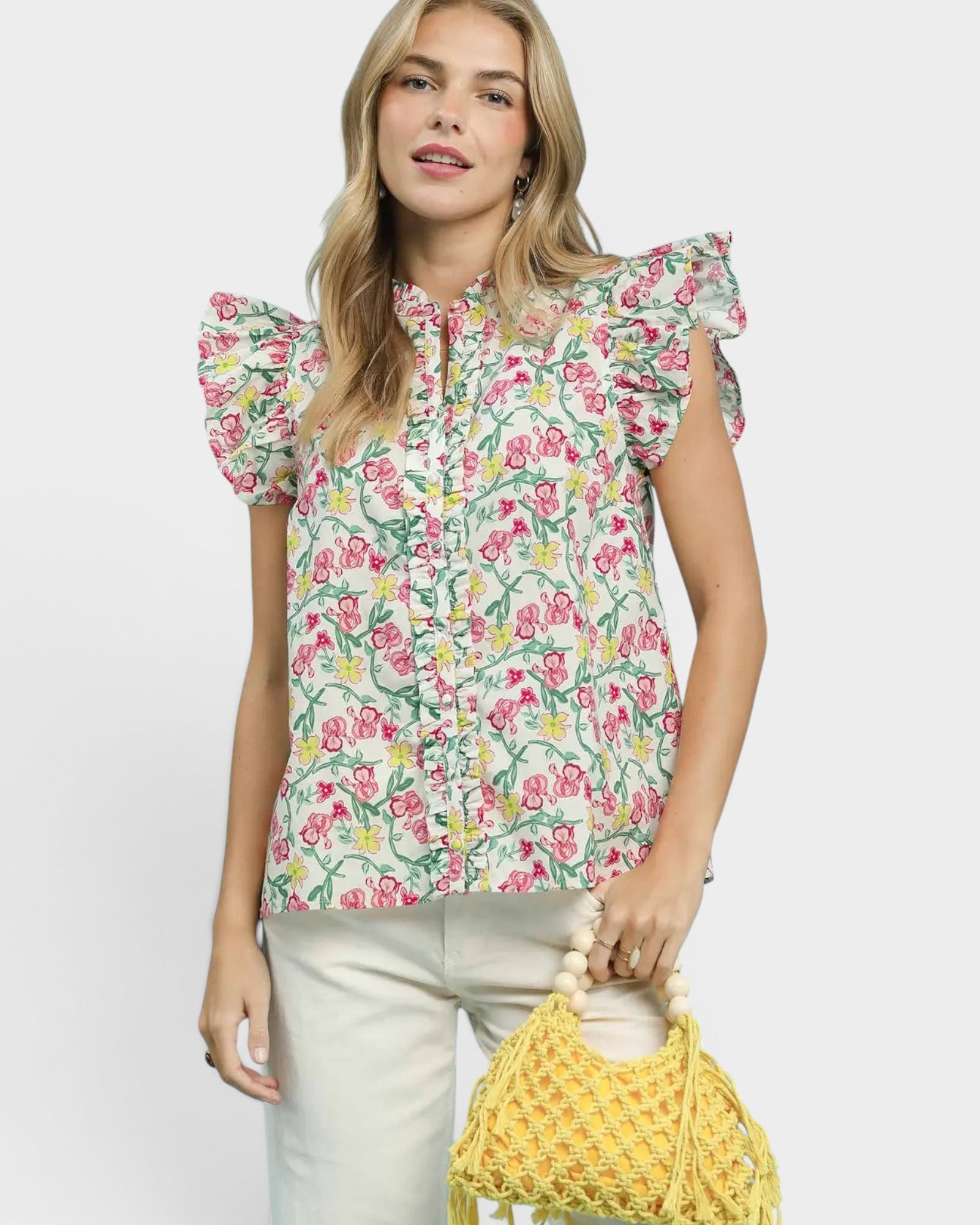 Woman wearing a floral blouse holding a yellow bag against a white background