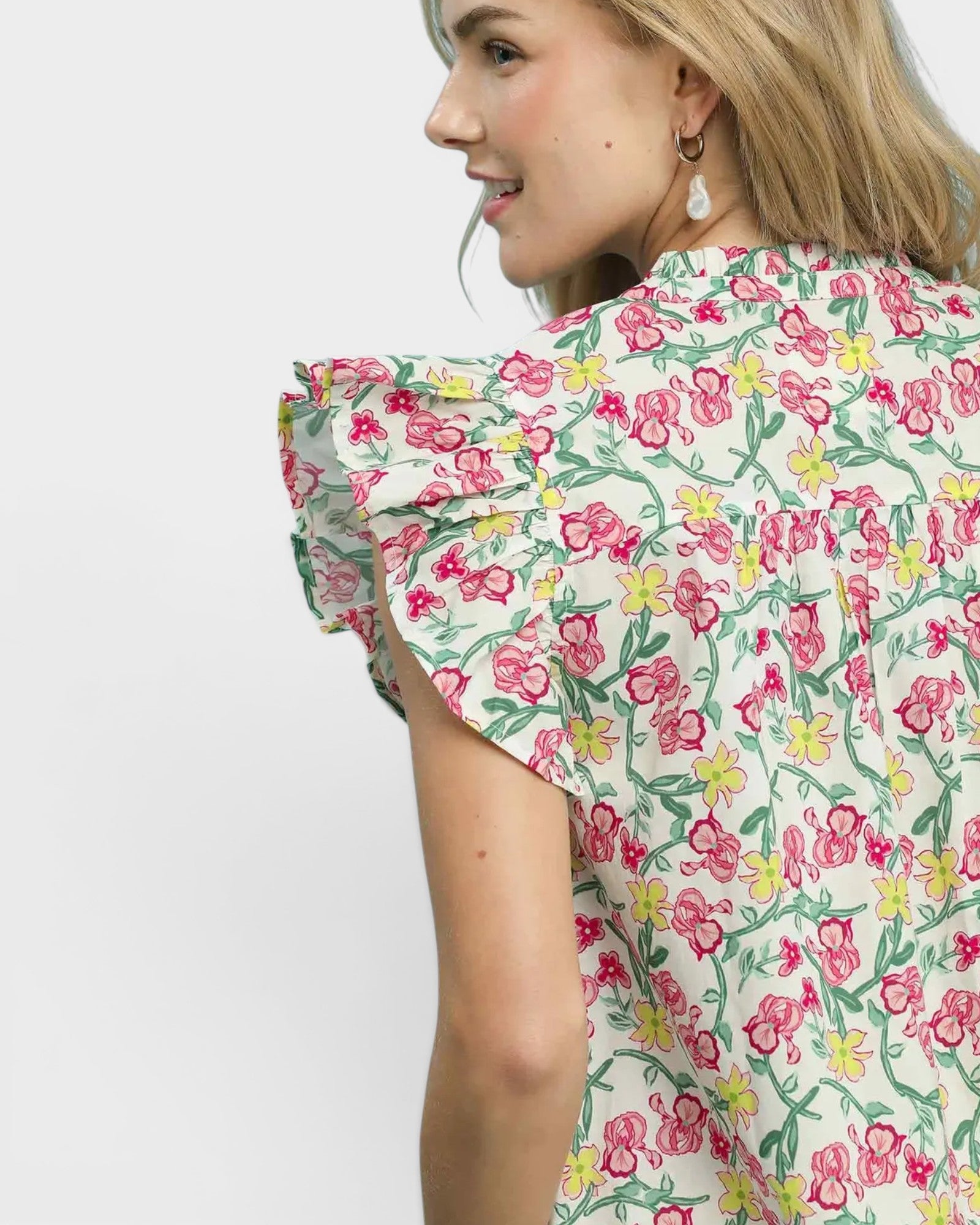 Woman wearing a floral dress with ruffled sleeves on a plain background