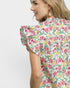 Woman wearing a floral dress with ruffled sleeves on a plain background