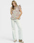 Woman wearing a floral blouse and white pants on a white background