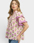 Woman wearing a floral blouse with ruffled sleeves on a plain background
