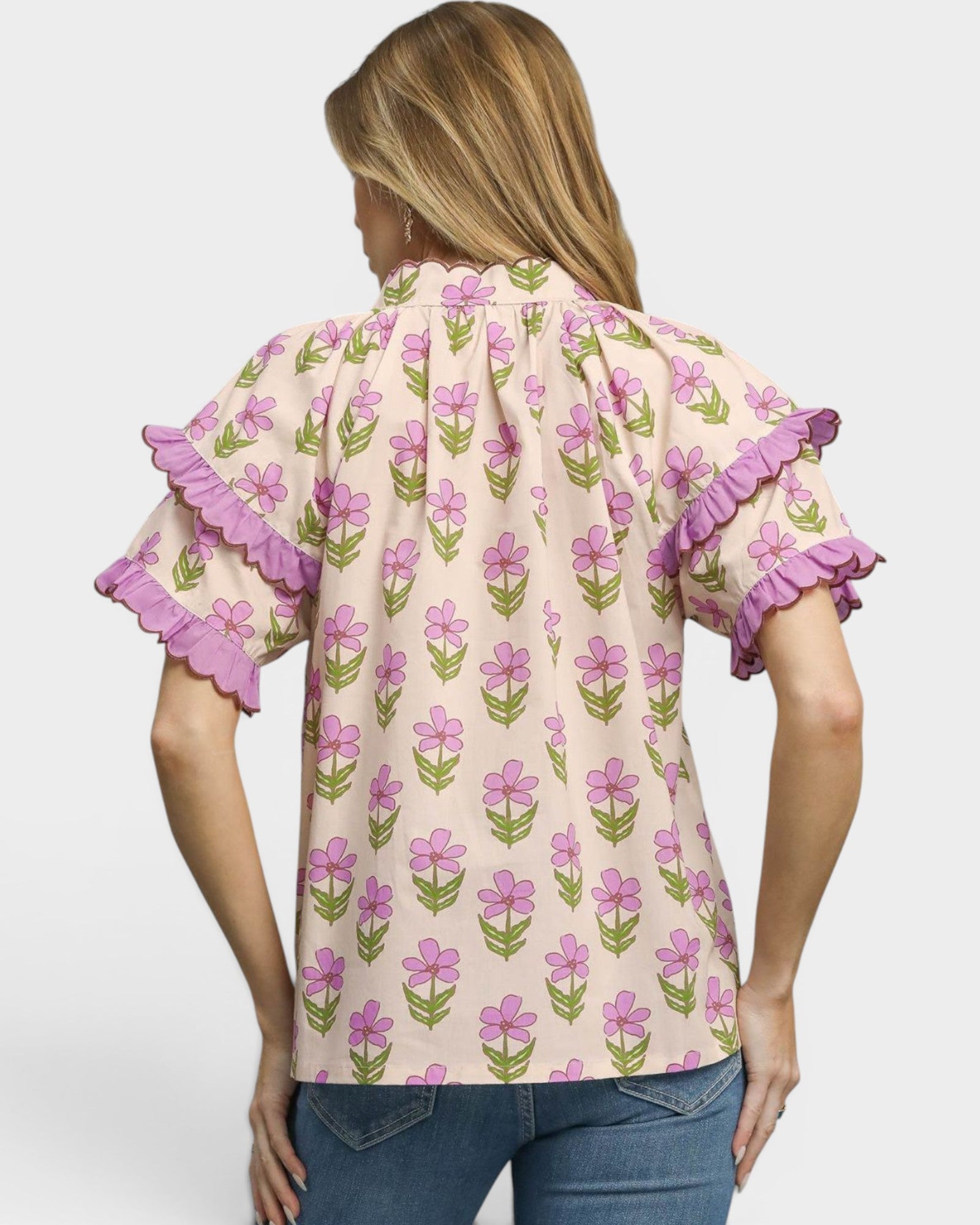 Woman wearing a floral blouse with ruffled sleeves on a plain background