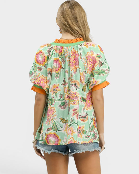 Woman wearing a floral blouse with orange trim on a white background
