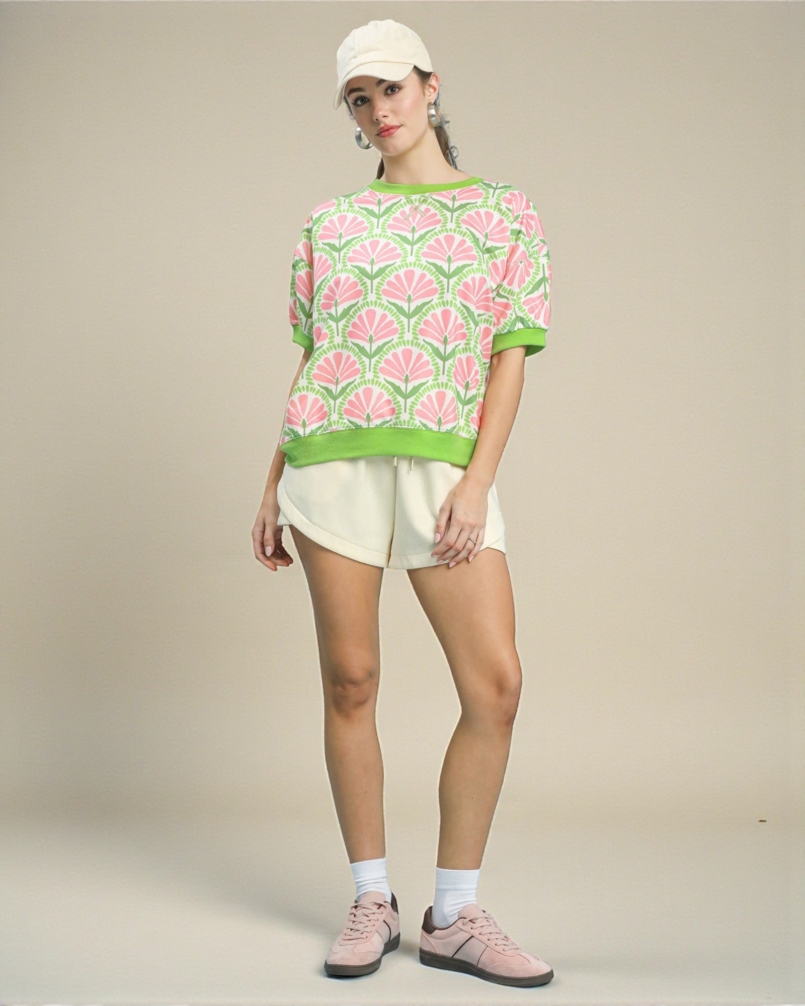 Person wearing a patterned sweater, shorts, and sneakers on a plain background