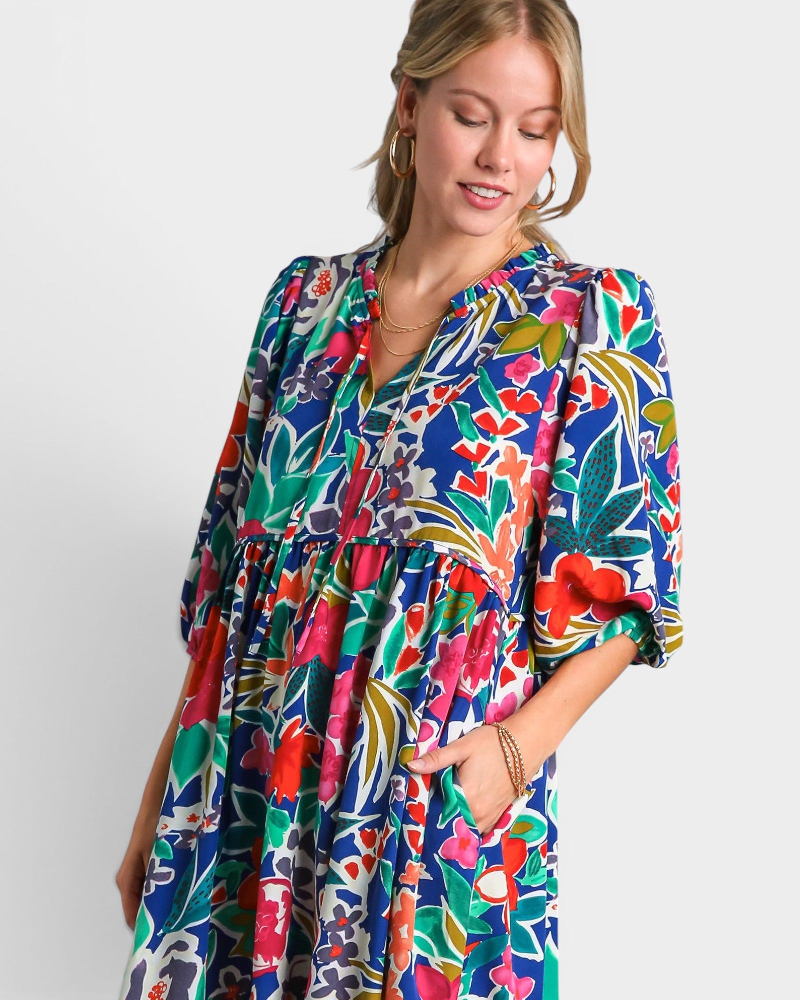 Woman wearing a colorful floral dress against a white background