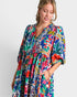 Woman wearing a colorful floral dress against a white background