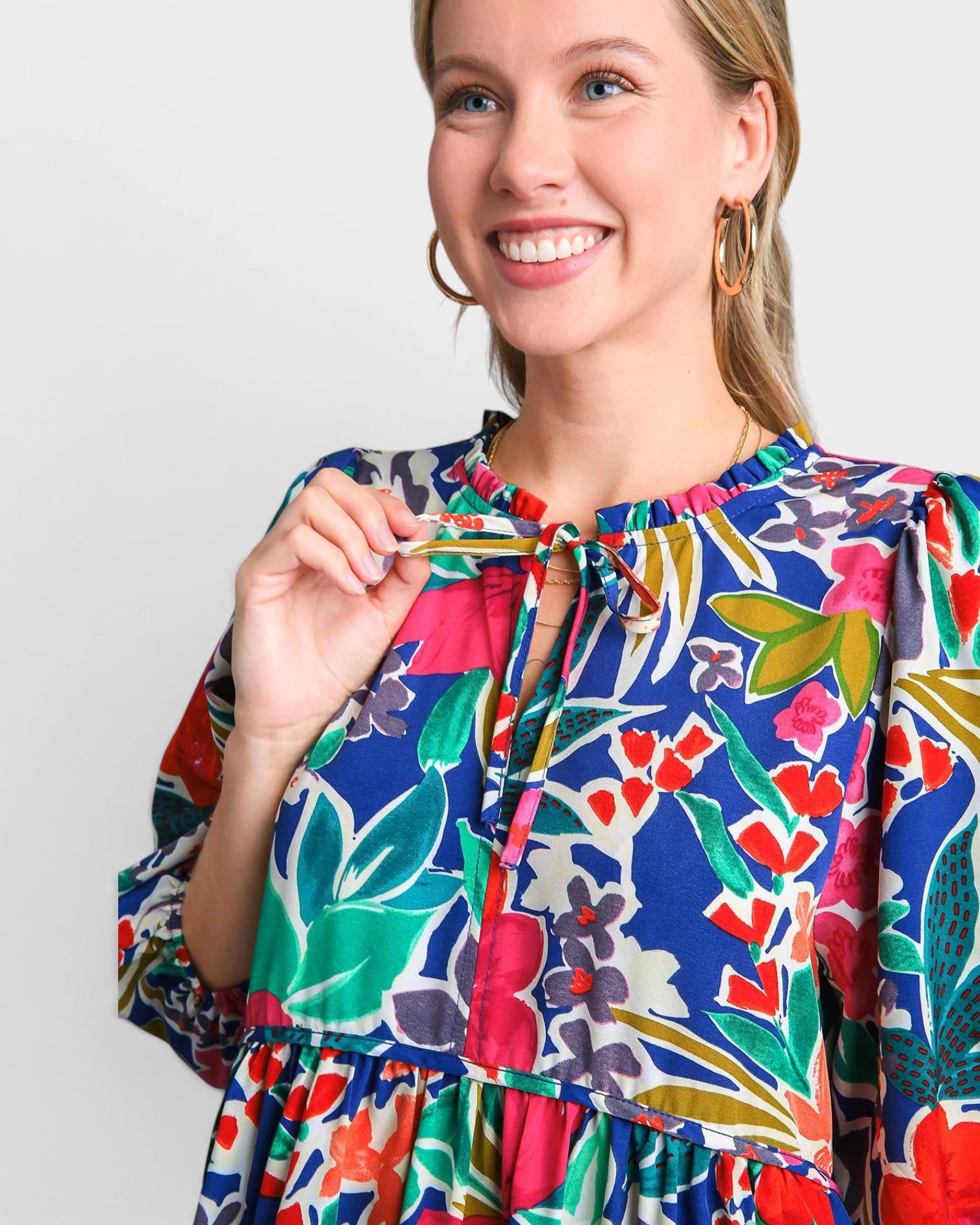 Woman wearing a colorful floral dress against a plain background