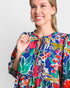 Woman wearing a colorful floral dress against a plain background