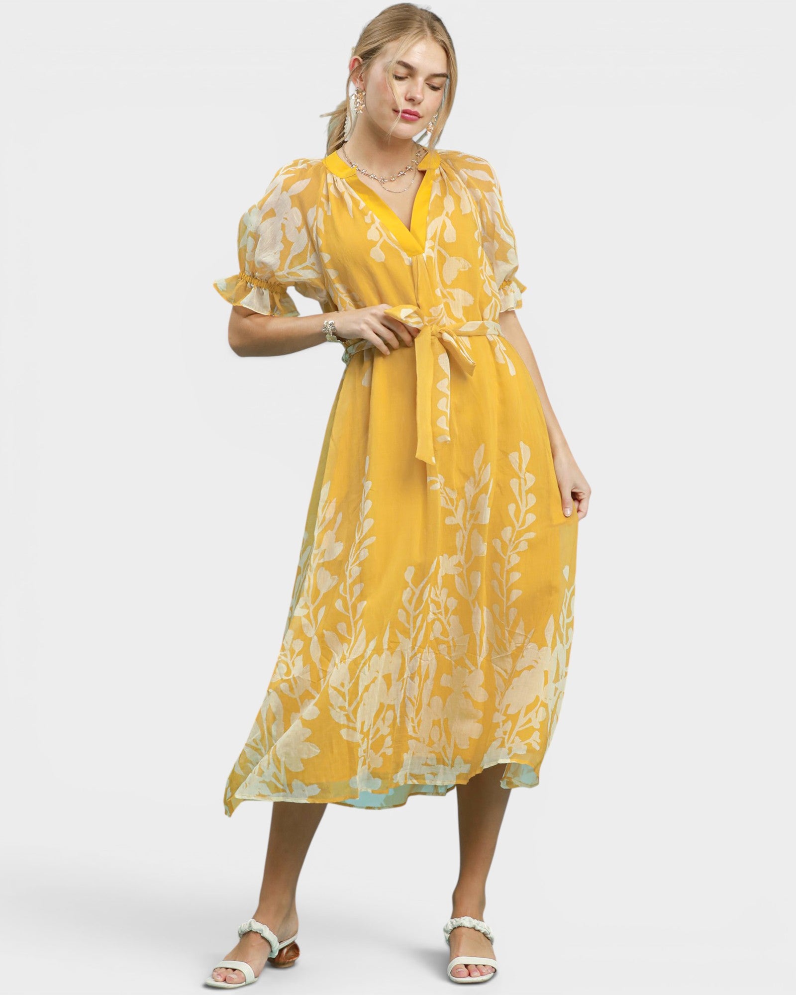 Woman wearing a yellow floral dress on a white background