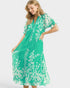 Woman wearing a green dress with white floral pattern on a white background