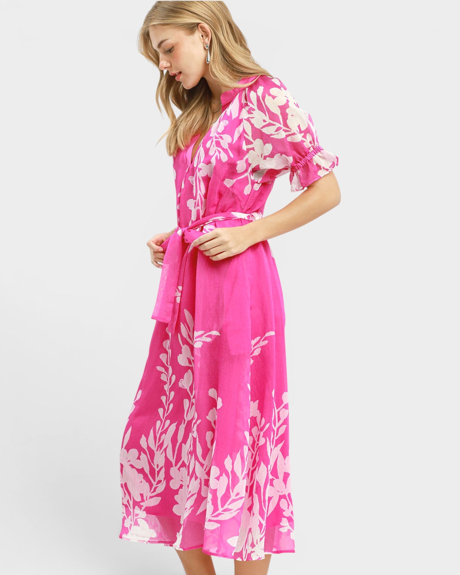Woman wearing a pink dress with white floral pattern on a white background