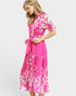 Woman wearing a pink dress with white floral pattern on a white background