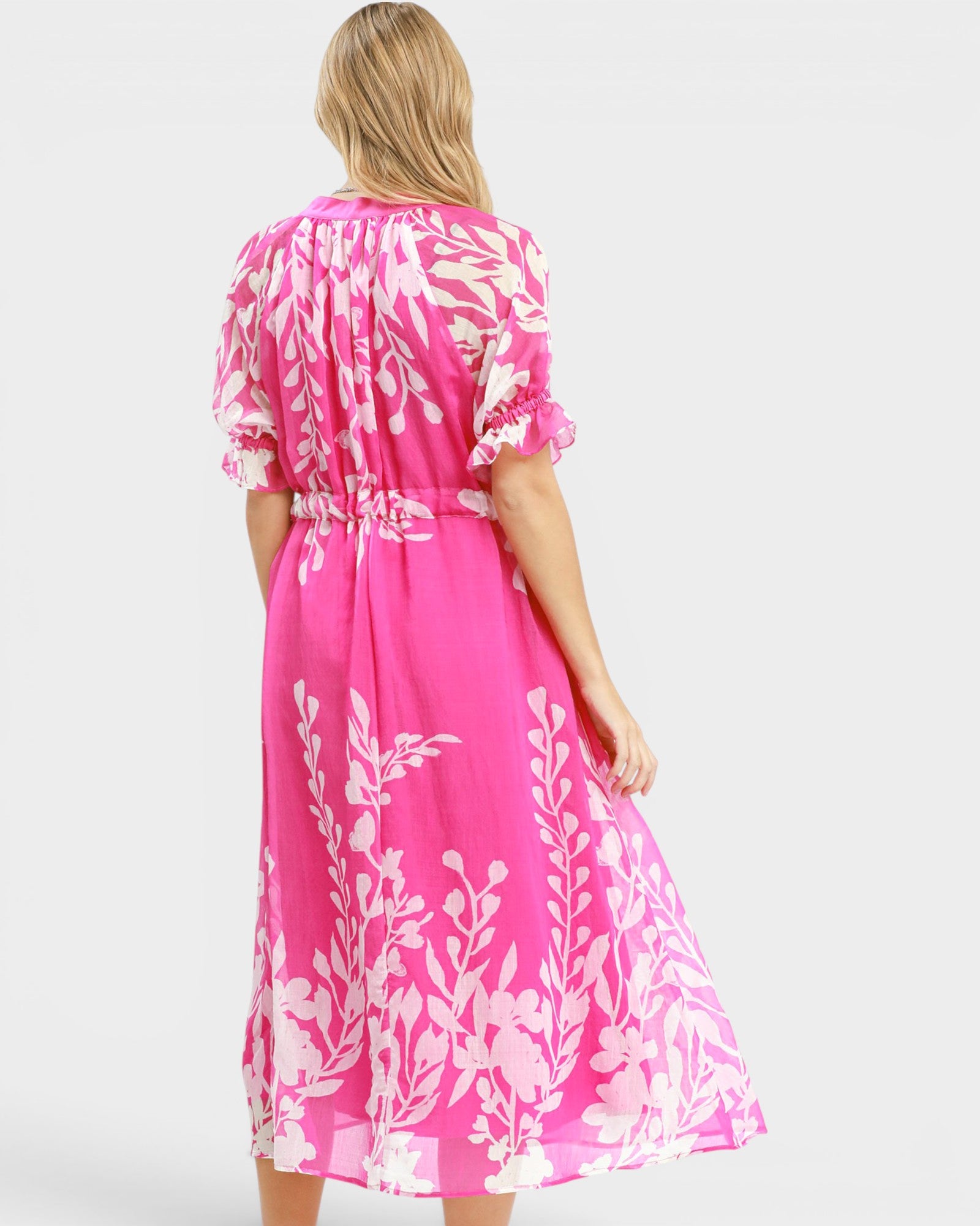 Woman wearing a pink dress with white floral pattern on a white background