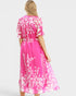 Woman wearing a pink dress with white floral pattern on a white background