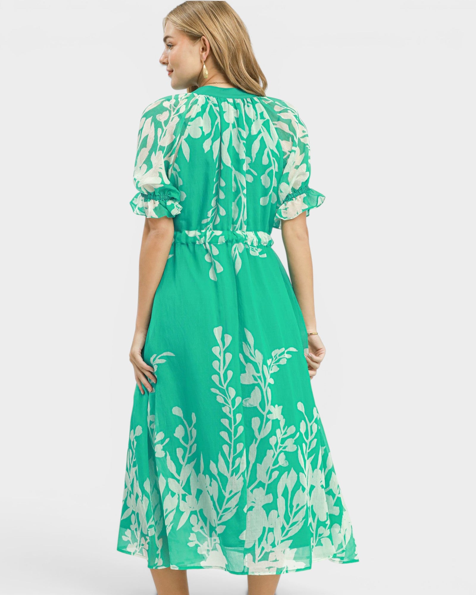 Woman wearing a green dress with white floral pattern on a white background