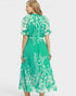 Woman wearing a green dress with white floral pattern on a white background