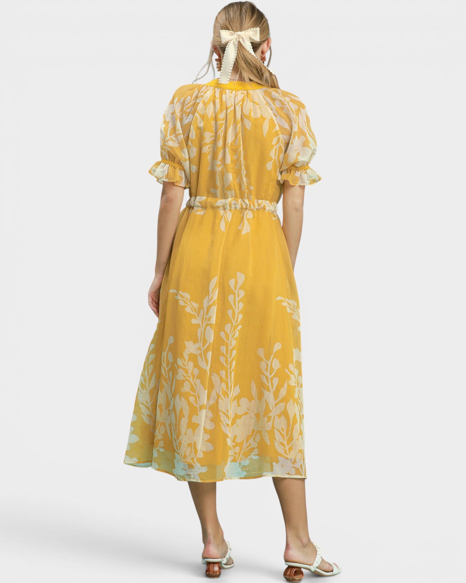 Woman wearing a yellow floral dress on a white background