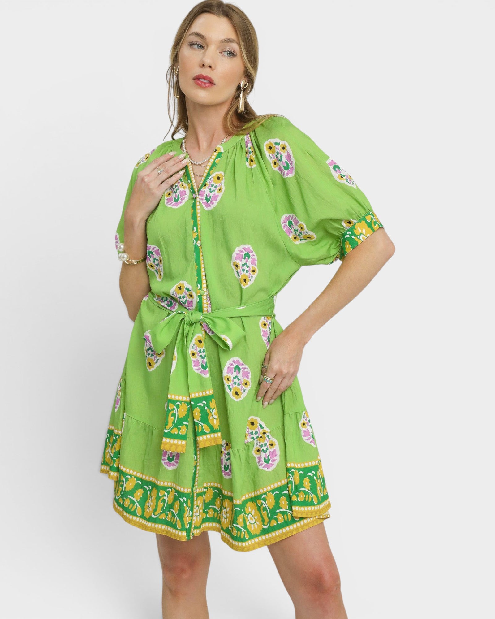 Woman wearing a green dress with floral patterns on a white background