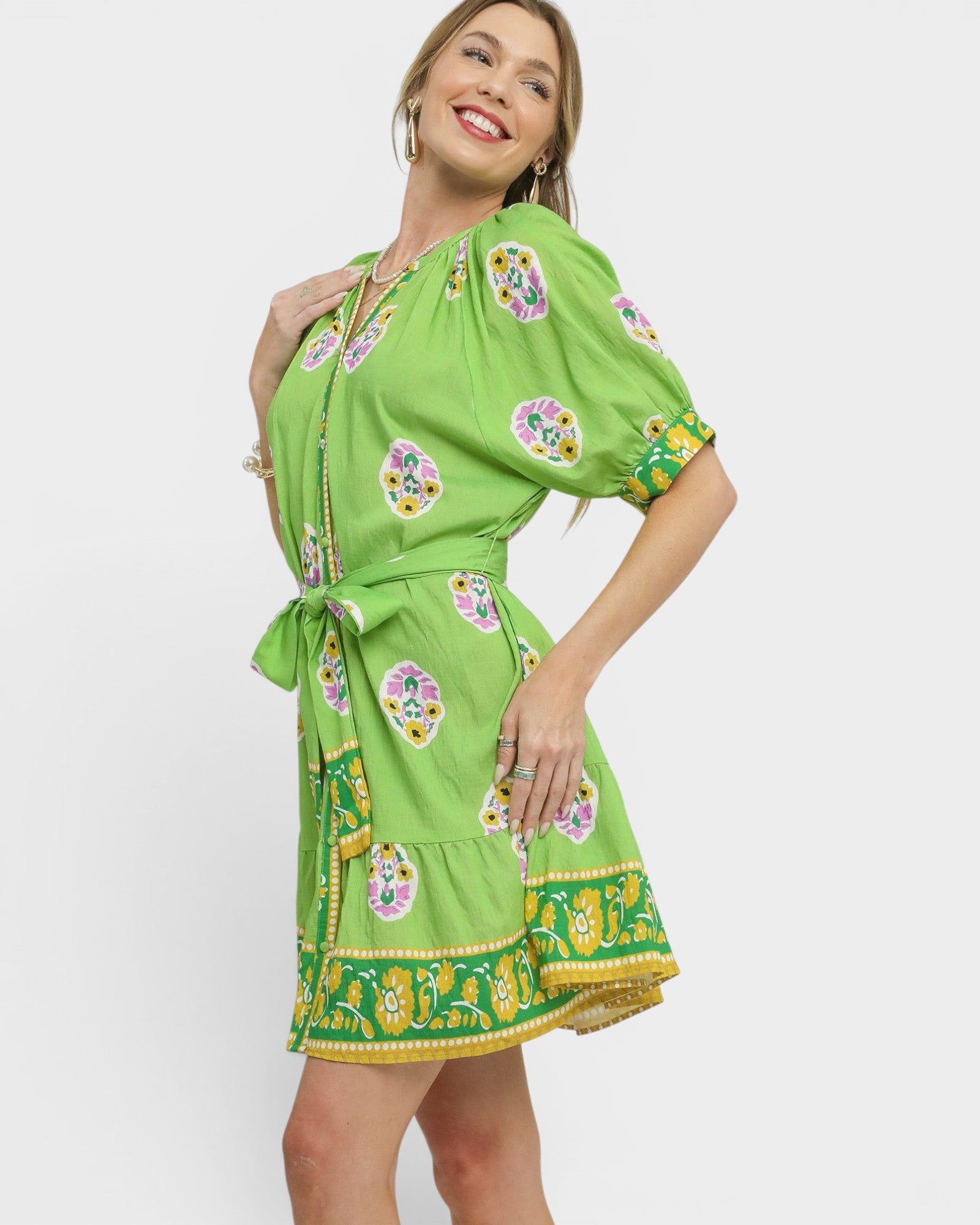 Woman wearing a green dress with floral patterns on a white background