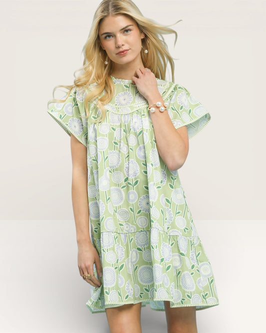 Woman wearing a green floral dress against a plain background