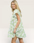 Woman wearing a green floral dress against a plain background